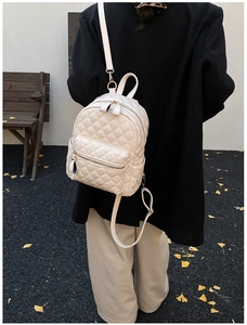 Détail d'un sac à dos matelassé beige avec fermetures éclair dorées en décor d'automne
