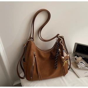 Détail d'un sac cabas en cuir marron avec charm d'ours et accents de zip métalliques