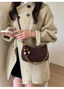 Détail du sac demi-lune en daim marron avec chaîne dorée et pompon rétro perlé