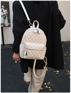 Close-up of beige quilted PU leather mini backpack with elegant gold zippers and hardware