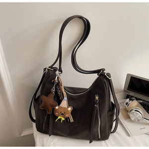 Détail d'un sac en cuir marron avec double fermeture éclair et pendentif ours mignon
