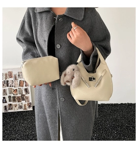 Detail of off-white lychee leather bucket bag with metal buckle and rabbit charm