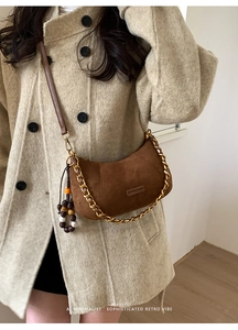 Détail du sac demi-lune en daim marron avec pompon perlé et bandoulière dorée