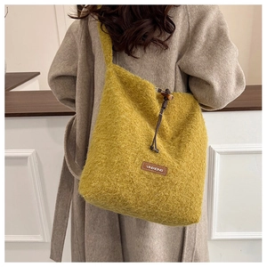 Close-up of fluffy yellow faux fur tote bag featuring a leather logo patch and drawstring