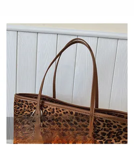 Detail of leopard print tote bag featuring brown leather handle and cute plush charm