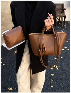 Dettaglio borsa tote in pelle marrone morbida con pochette e ciondolo in legno