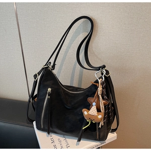 Détail du sac hobo en cuir noir avec zips argentés et breloque ours en peluche