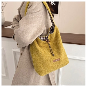 Close-up of fluffy yellow faux fur tote bag featuring a leather logo and wooden toggle button