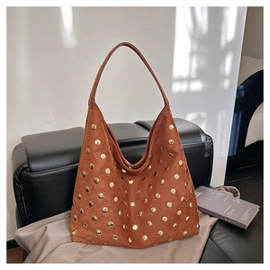 Detail of vintage brown suede hobo bag with gold metal rivets on a leather chair
