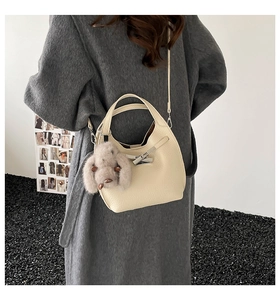 Detail of off-white lychee grain leather bucket bag with cute plush rabbit charm