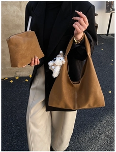Detail of brown suede tote bag with white contrast stitching and plush bear charm