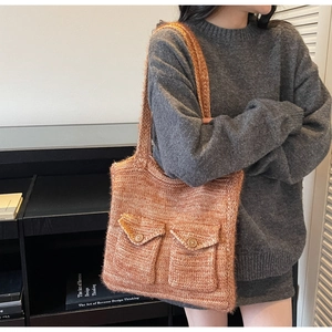 Détail du sac fourre-tout en tricot brun-rouge avec doubles poches boutonnées et texture souple