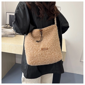 Detail of camel plush shoulder bag featuring drawstring closure and leather brand patch