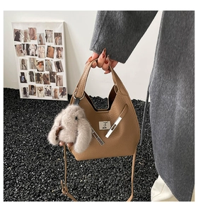 Detail of brown leather bucket bag with silver H-buckle and plush rabbit charm