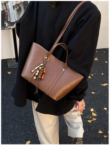 Dettaglio della borsa tote in pelle marrone scuro con nappa di perline in strada