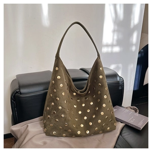 Close-up of olive green suede hobo bag with decorative gold studs on a leather bench