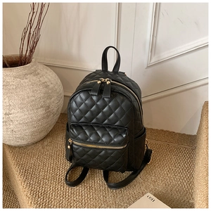 Détail d'un sac à dos noir en similicuir matelassé avec fermetures éclair dorées chic