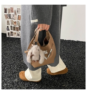 Detail of brown litchi pattern leather bucket bag with cute plush rabbit keychain