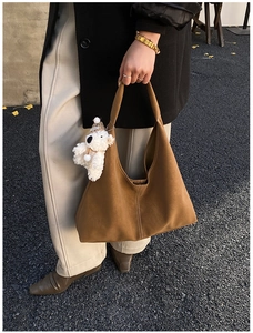 Chic caramel hobo bag featuring a plush bear charm and decorative vertical stitching detail