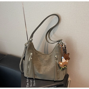 Détail du sac hobo marron olive avec fermetures éclair multiples et pendentif ours