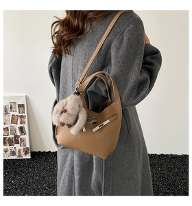Close-up of lychee grain leather bucket bag with metal buckle and plush rabbit charm
