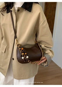 Détail du sac hobo rétro en suède avec pompon en bois et chaîne dorée