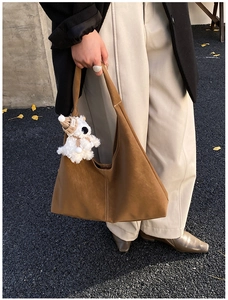 Detailed view of caramel suede tote bag featuring a decorative plush bear charm and stitching