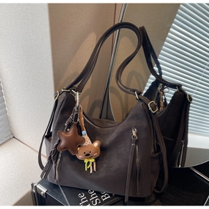 Détail du sac bandoulière en cuir mat marron foncé avec breloques étoile et ours