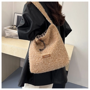 Detail of a brown fuzzy bucket bag with brand leather patch and plaid fabric lining