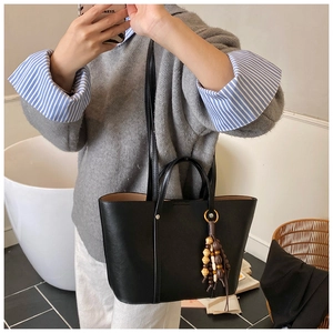 Detail of black matte leather tote bag with vintage wooden beads and shoulder strap