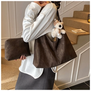 Detail of dark brown hobo shoulder bag with a matching pouch and a teddy bear charm