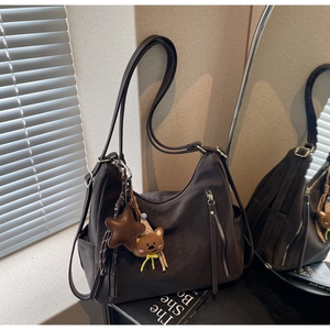 Détail du sac hobo marron foncé avec charm d'ours et texture en cuir mat souple