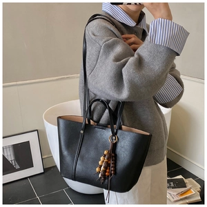 Dettaglio della borsa tote in pelle nera vintage con nappa di perline di legno sulla tracolla