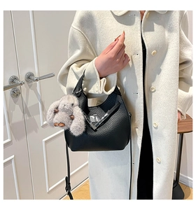 Detail of black pebble leather bucket bag with silver clasp and plush bunny charm