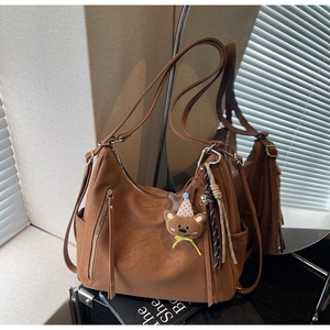 Détail du sac en similicuir marron avec fermetures éclair et pendentif ours doux