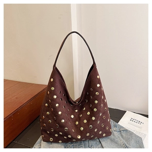 Detail of vintage brown suede Hobo bag with decorative gold rivets on denim background