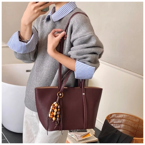 Dettaglio della borsa tote in pelle bordeaux con ciondolo unico in perline di legno colorate