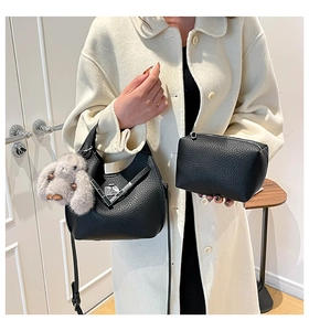 Detail of black pebbled leather bucket bag set with silver hardware and plush bunny charm