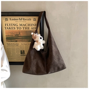 Detailed view of large dark brown tote bag with retro matte leather and plush bear charm