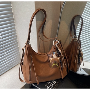 Détail d'un sac hobo marron vintage avec fermetures éclair et charmant ours en peluche