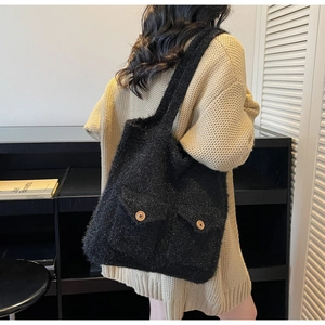 Detailed side view of a large black plush tote bag with wooden buttons and pockets