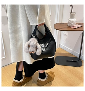 Detail of black lychee grain leather bucket bag with cute plush bunny charm and silver buckle