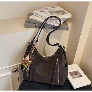Gros plan sur un sac bandoulière vintage en nubuck marron avec pendentif ourson