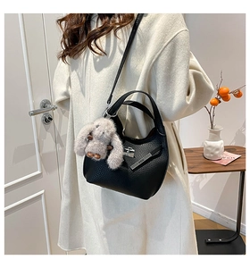 Close-up of black lychee texture bucket bag featuring metal lock and cute rabbit plush charm