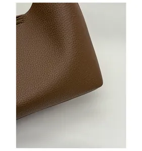 Close-up detail of dark brown bucket bag showing high-quality lychee grain leather and stitching