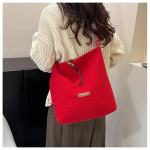 Detail of red wool felt tote bag with brown leather brand tag and drawstring closure