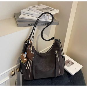 Détail d'un sac Hobo en daim avec fermetures éclair argentées et breloques mignonnes