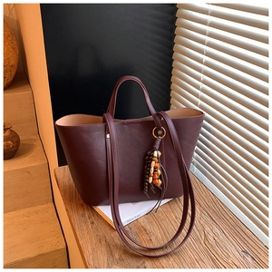 Dettaglio della borsa tote in ecopelle bordeaux con ciondolo decorativo in perline di legno