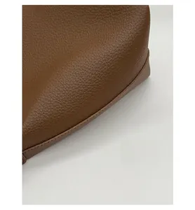 Close-up of precise stitching and pebble grain texture on a brown leather bucket bag