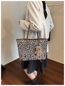 Detail of leopard print tote bag with brown shoulder strap and teddy bear charm
